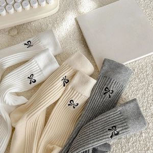 Three pairs of cotton ribbed socks with black bow embroidery in white, beige and dark grey