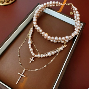Close-up of pink pearl layered necklace and golden cross pendants in a gift box