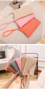 Detail of woven straw clutch bags in various colors with wrist straps and zippers