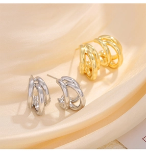 Detail of overlapping geometric hoop earrings in gold and silver on silk fabric