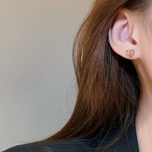 Close-up of golden knot earrings on model ear showing elegant texture and size