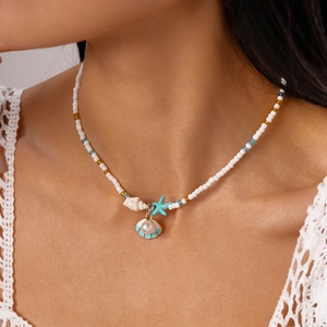 Detail of beaded sea necklace with starfish, shell charms and pearls on model's neckline