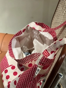 Détail du sac en toile à pois rouges avec étiquette cousue Simple Wish sur le côté