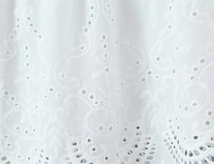 Detail of white cotton eyelet embroidery with floral patterns and delicate cutout texture