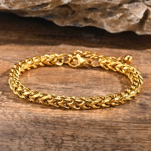 Close-up of golden wheat link chain bracelet with lobster clasp on rustic wood background