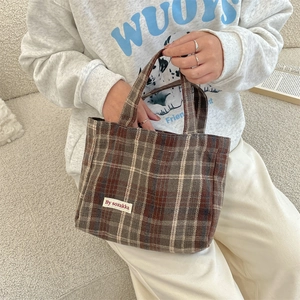 Close-up of vintage plaid tote bag featuring a stitched brand label and woven texture