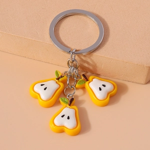 Detail of yellow cartoon pear charm on a metal keychain featuring high quality finish