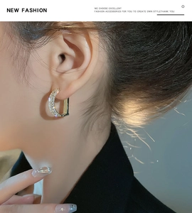 Close-up detail of gold C-shaped earrings with micro-pave zircons worn on ear