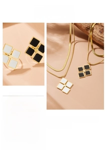 Detail of gold-tone necklace and stud set with black and white square clover motifs