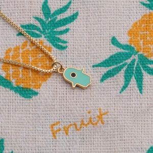 Detailed view of gold plated Hamsa hand pendant with light blue enamel and evil eye charm