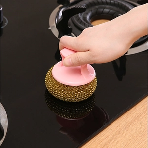 Kitchen scrubbing brush with pink handle and golden metal wire ball for stove cleaning