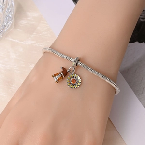 Silver bracelet detail featuring sunflower and gnome charms on a model's wrist