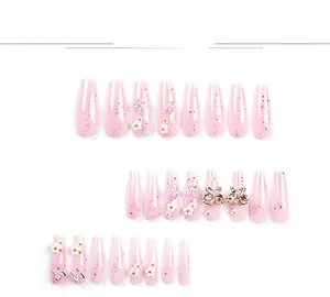 Detail of pink glitter press-on nails with 3D white flowers and silver metal butterflies
