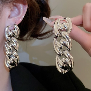 Close-up of polished silver chunky chain earrings worn and held for detail