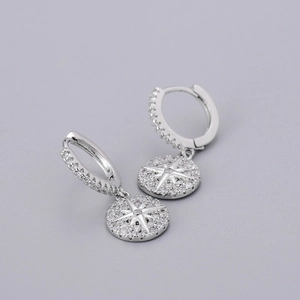 Detail of silver hoop earrings featuring starburst charms with sparkling zircon pavé