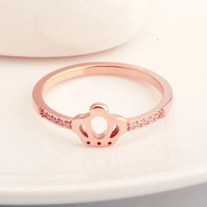 Fashionable rose gold crown ring with sparkling micro-pave crystals on white surface