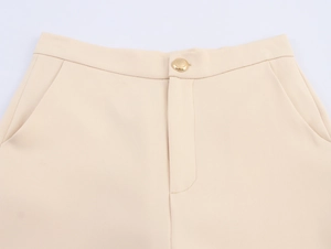Detail of apricot suit trousers featuring golden button and seamless zip closure