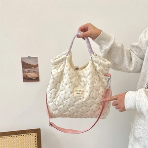 Détail d'un sac bandoulière fleuri matelassé avec anses mauves et sangle rose réglable