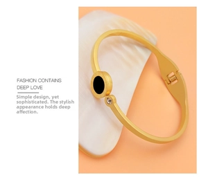 Detail of gold titanium bracelet with roman numerals, black inlay, and zircon accent