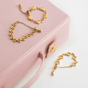 Detailed view of 18K gold plated stainless steel heart and clover chain rings in jewelry box