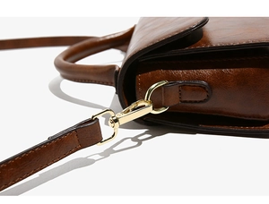 Dettaglio dell'hardware in metallo dorato e della trama in pelle marrone della borsa