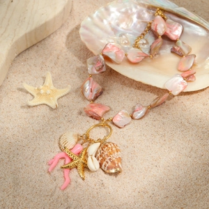 Ocean style necklace with pink shells and golden starfish on a beach background