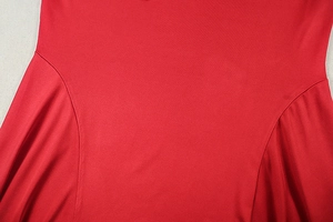 Detail of red pleated long sleeve dress showing fabric texture and curved seam stitching