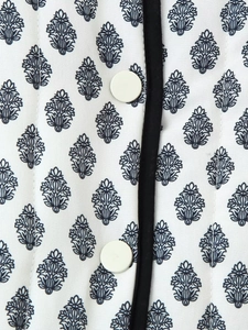 Detail of leaf print quilted cotton jacket with round white buttons and black piping