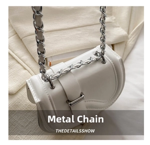 Detail of white mini saddle bag showing woven silver chain strap and metal clasp buckle