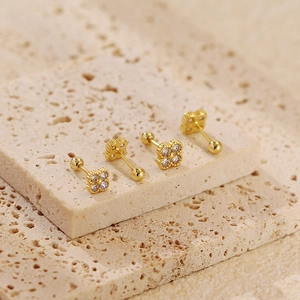 Macro view of gold clover earrings with sparkling zircon stones and secure screw backs