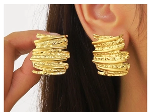 Detailed view of large gold-plated irregular textured earrings with a hammered finish