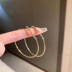 Gros plan de boucles d'oreilles créoles dorées brillantes montrant l'éclat et la grande taille