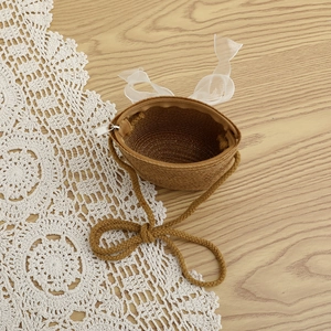 Close-up of children straw crossbody bag with white organza bow and zipper detail