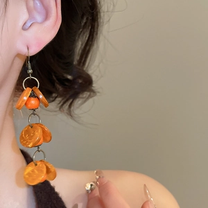 Détail de boucles d'oreilles bohèmes vintage avec perles orange sur un mannequin