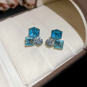 Macro view of geometric crystal earrings with sea blue stones on beige velvet display box