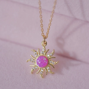 Close-up of a golden sun pendant necklace with pink opal and zircon micro-pave