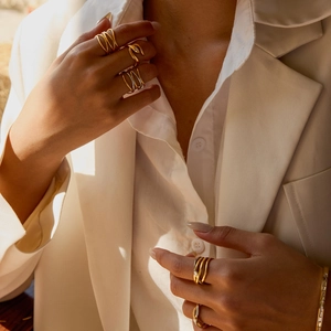 Detail of layered gold snake rings and wavy crossover bands on model fingers