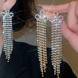 Close-up of silver long tassel earrings with sparkling rhinestones and bow design