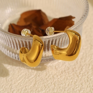 Minimalist 18K gold plated chunky C-shaped hoop earrings on a clear glass decorative bowl