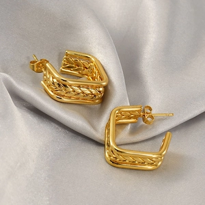 Golden multi-layer geometric woven texture hoop earrings on light gray silk fabric