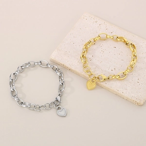 Close-up of gold and silver oval link bracelets with heart pendants and lobster clasps
