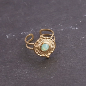 Macro d'une bague en acier doré avec pierre précieuse verte et anneau torsadé