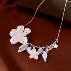 Detailed shot of silver snake chain necklace featuring a floral pendant and pearl charms