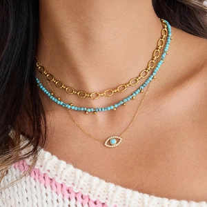 Three-layer gold necklace set with turquoise beads and evil eye pendant on a model
