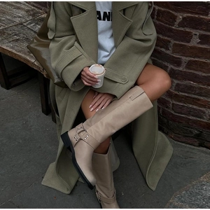Close-up of beige leather knee-high boots with metal ring buckle and chunky heel