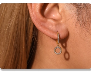 Detail of gold-plated geometric hoop earrings with hand-set cubic zirconia stones