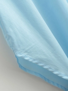 Detail view of light blue shirt hem with clean stitching and premium fabric texture