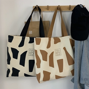 Close-up of canvas tote bag with abstract print and cartoon rabbit on a wooden hook