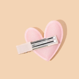 Cute pink velvet heart hair clip for girls with a silver metal duckbill base on beige background