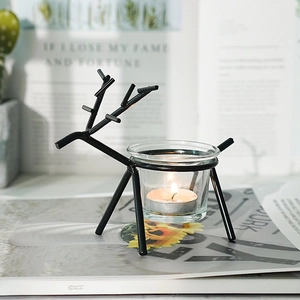 Close-up of Nordic iron deer tealight candle holder with glass cup on magazine prop.